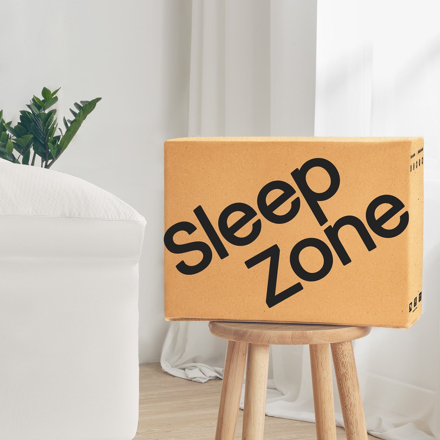 Cardboard box labeled 'Sleep Zone' on a wooden stool with a white curtain and plant in the background