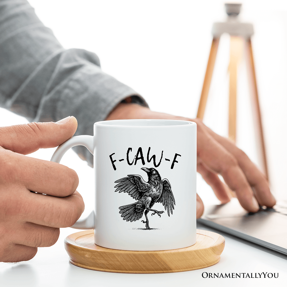 Person holding a mug with a bird design and text, sitting at a desk.