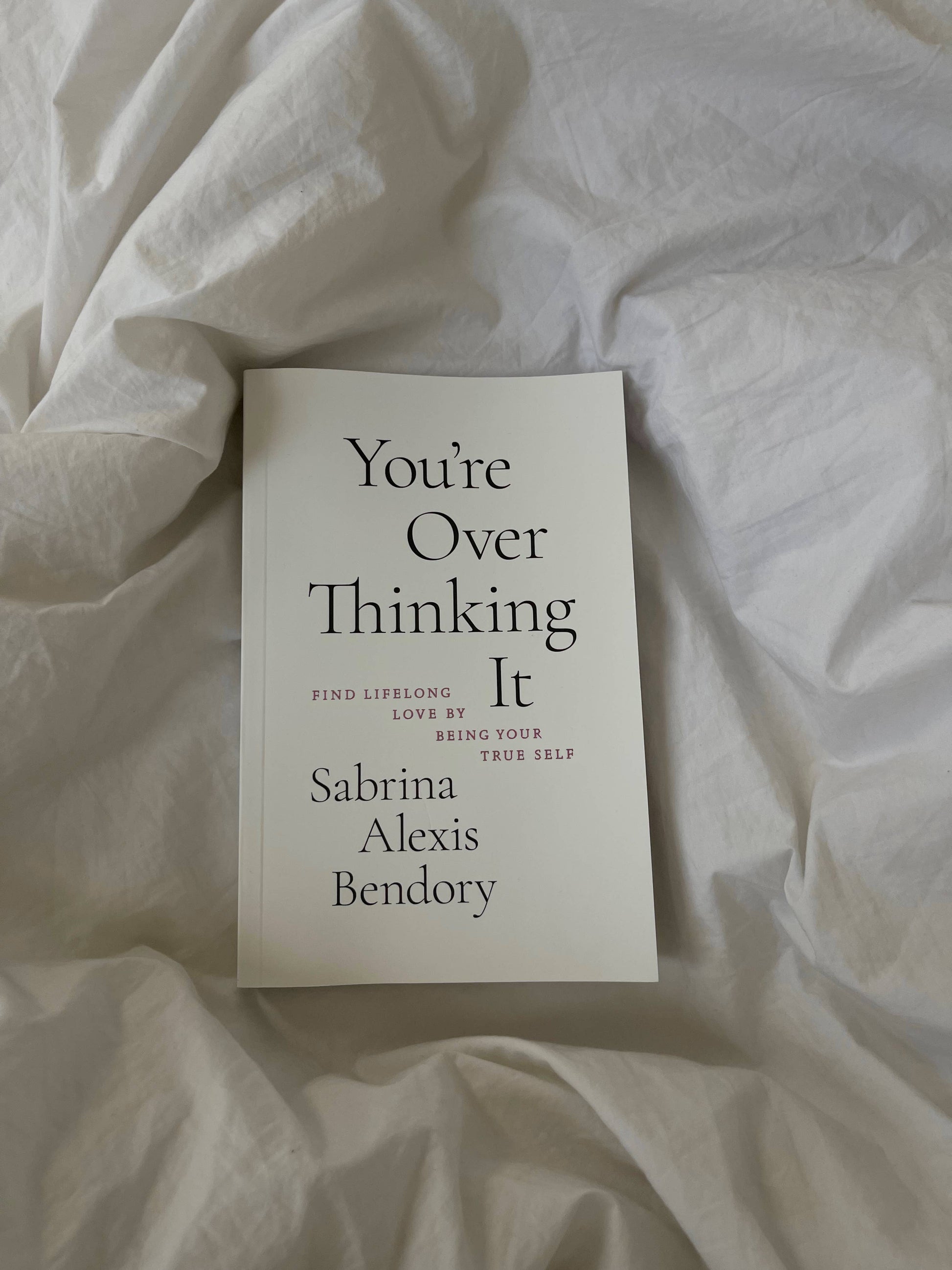 Book titled 'You're Over Thinking It' by Sabrina Alexis Bendory on a white fabric background