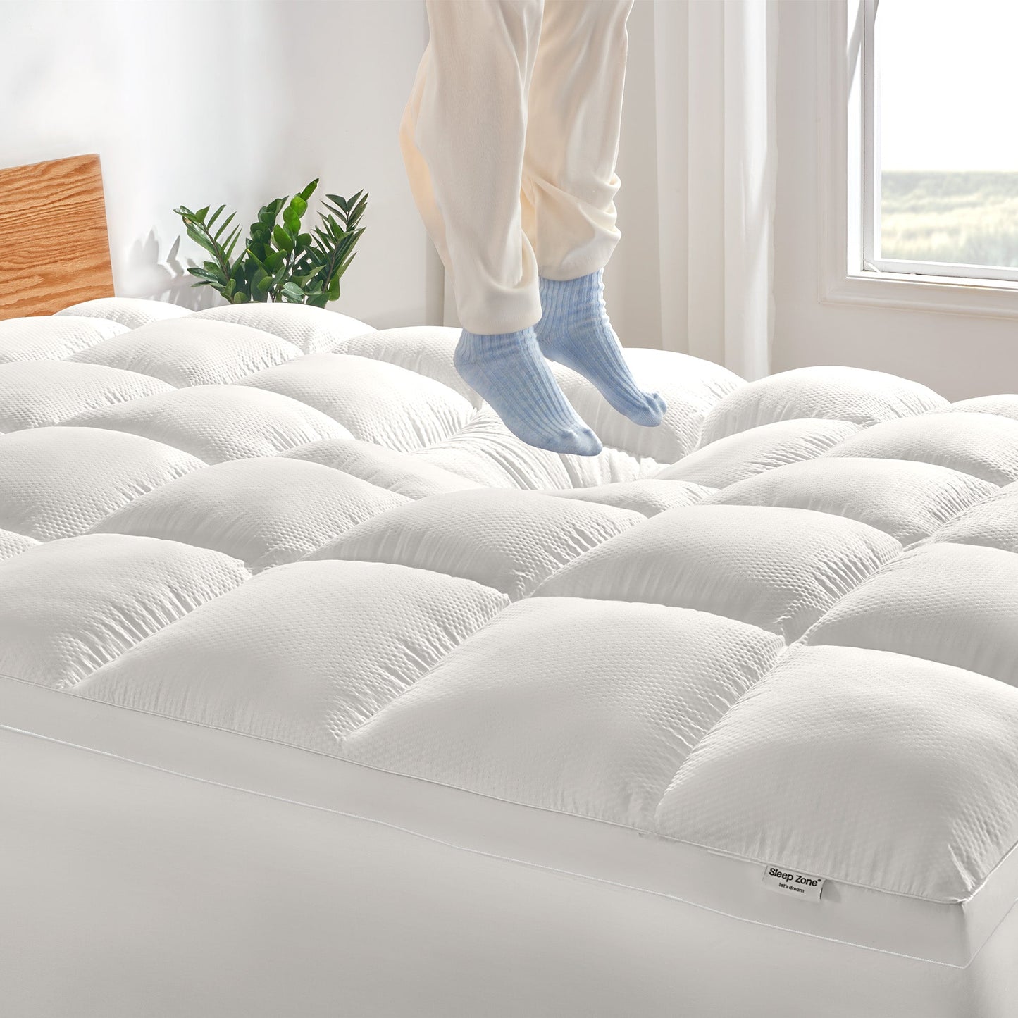 White mattress topper on a bed with a person standing in the background
