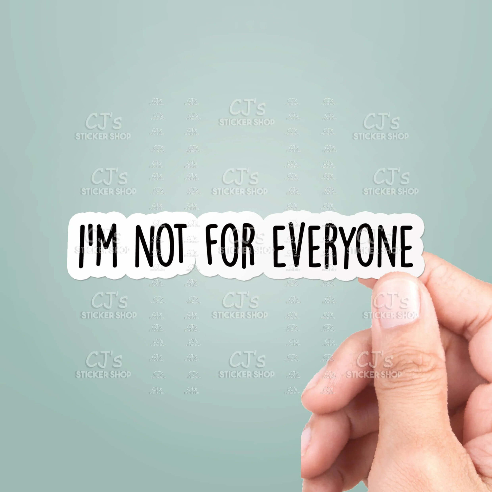 Hand holding a sticker with 'I'm not for everyone' text against a light blue background.