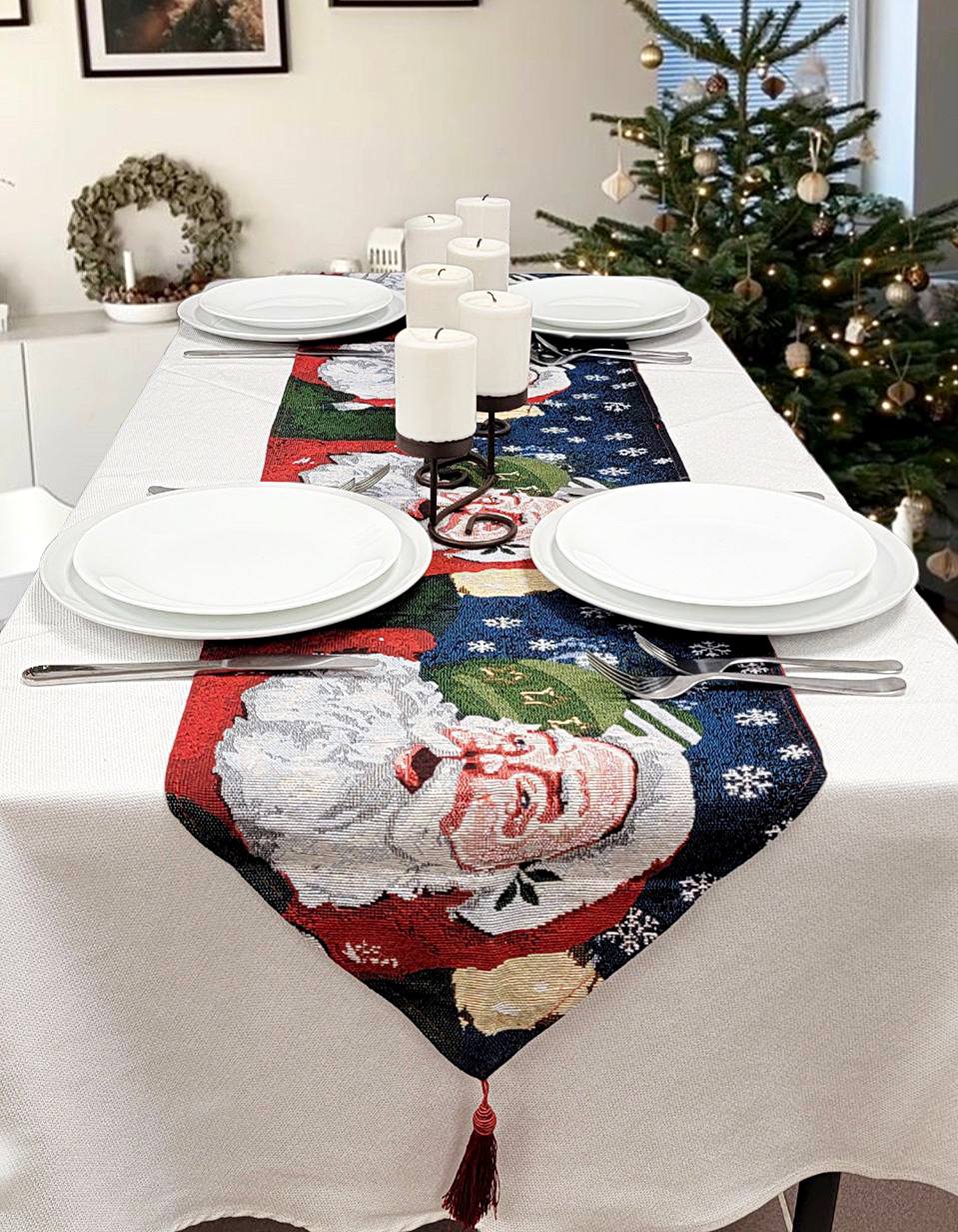 Dining table set for Christmas with a Santa Claus table runner, candles, and a decorated tree.