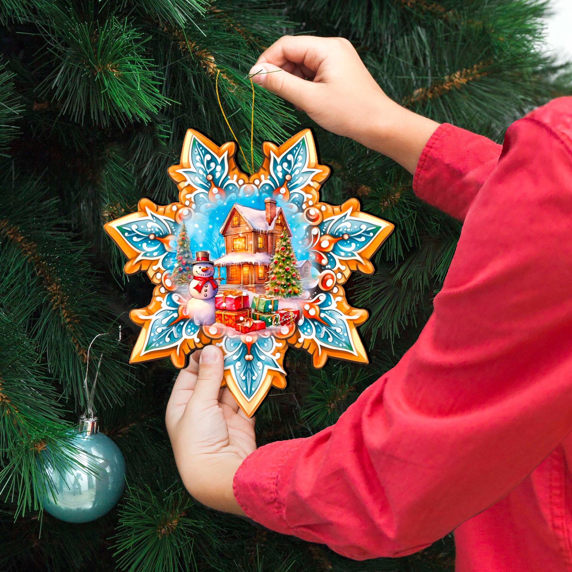 Person hanging a decorative Christmas ornament on a tree