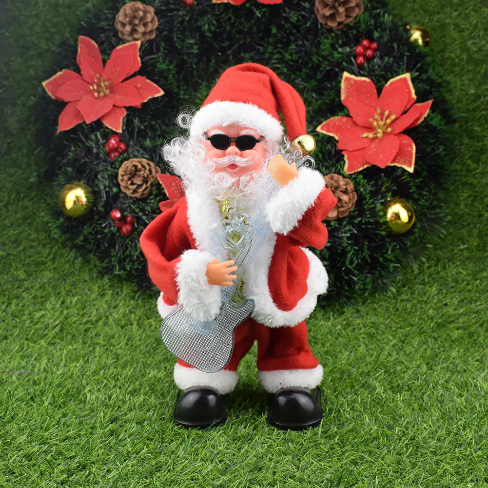 Decorative Santa Claus figure with sunglasses holding a gift bag, standing on grass with a Christmas tree in the background.