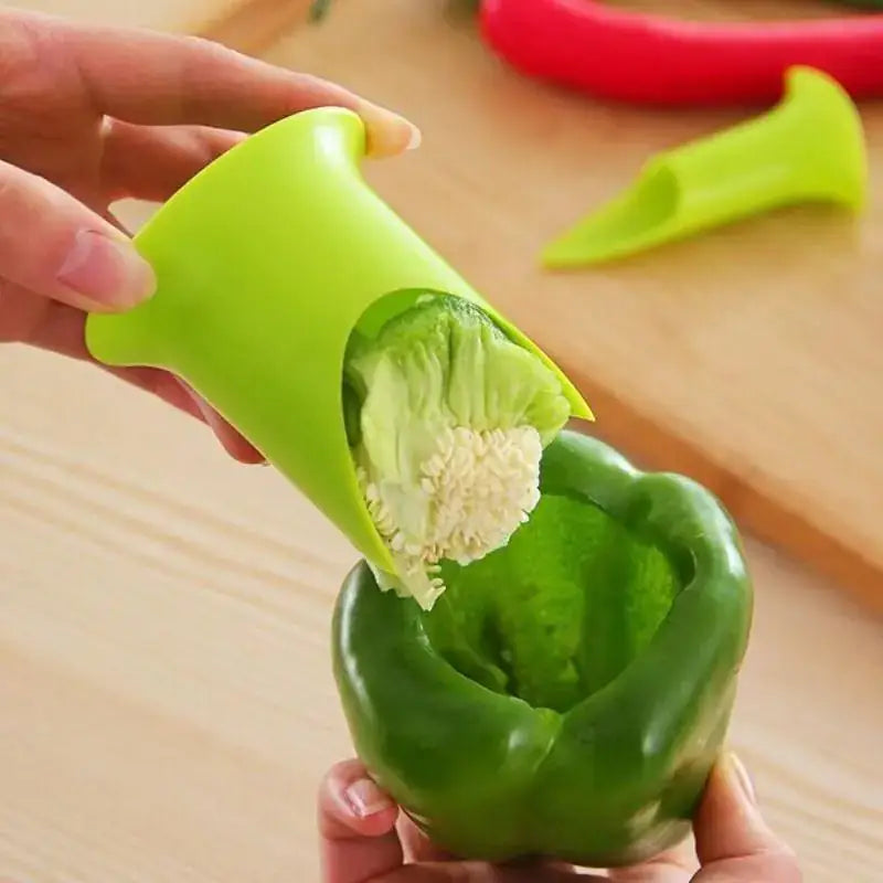 Green pepper being deseeded with a tool on a wooden surface
