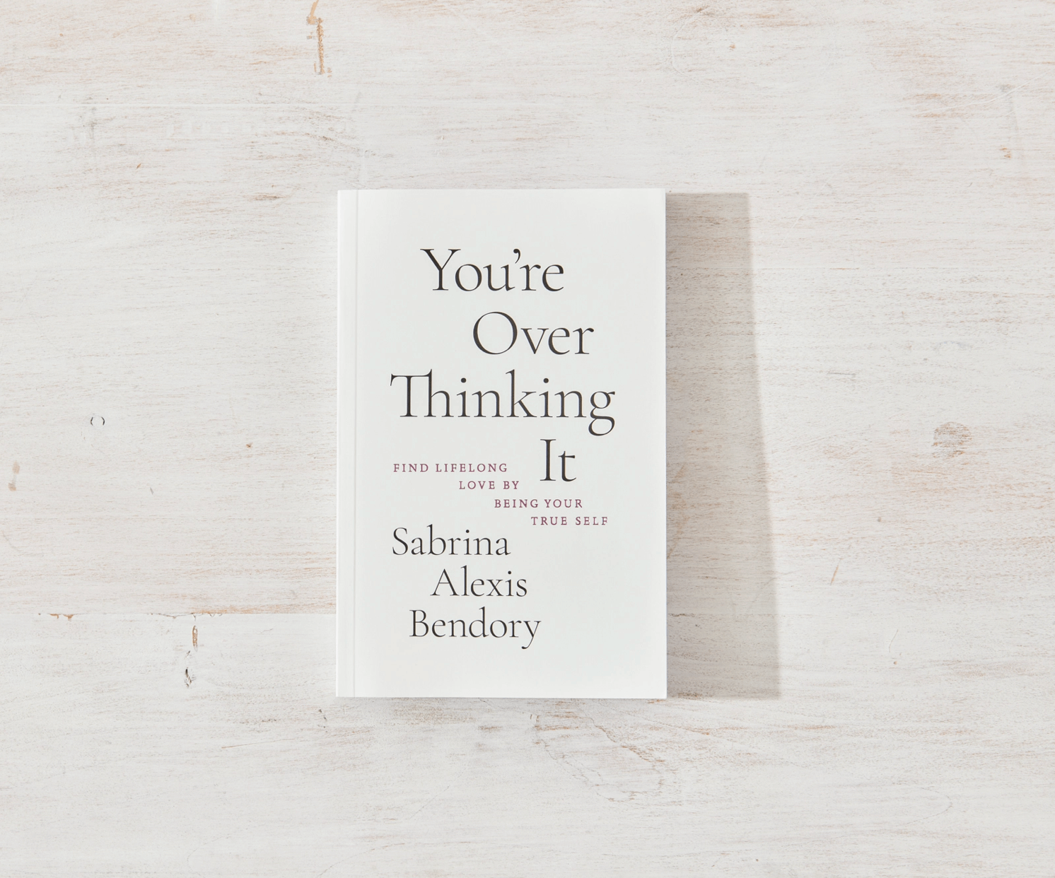 Book titled 'You're Over Thinking It' by Sabrina Alexis Bendory on a light wooden surface