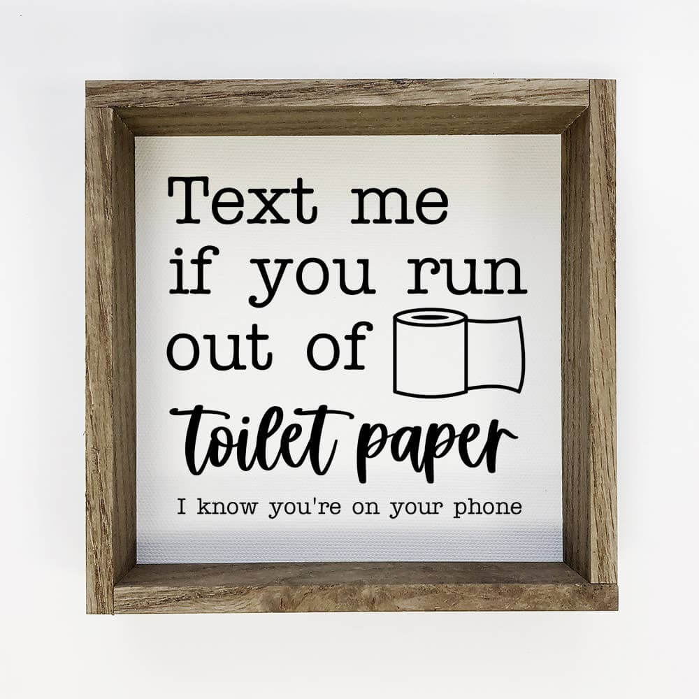 Wooden-framed sign with humorous text about toilet paper on a white background
