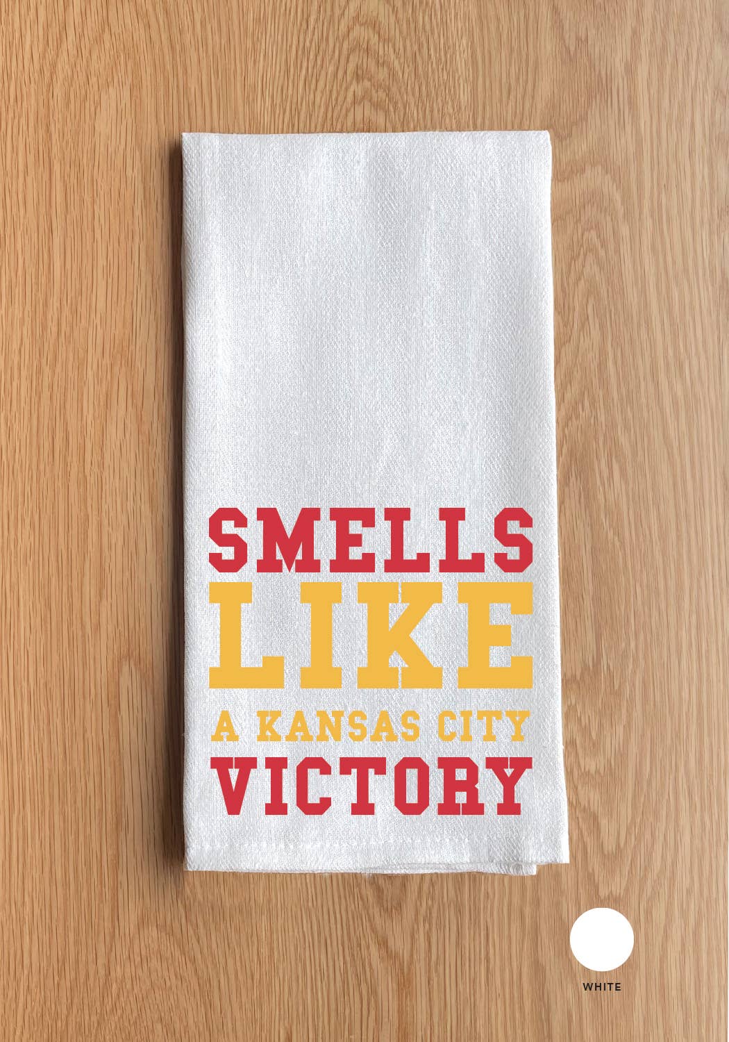White towel with 'Smells Like a Kansas City Victory' text on a wooden surface