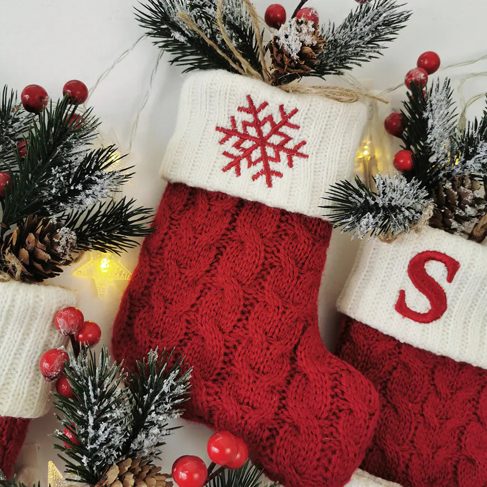 Red Christmas stockings with snowflake and 'S' design, surrounded by festive decorations.