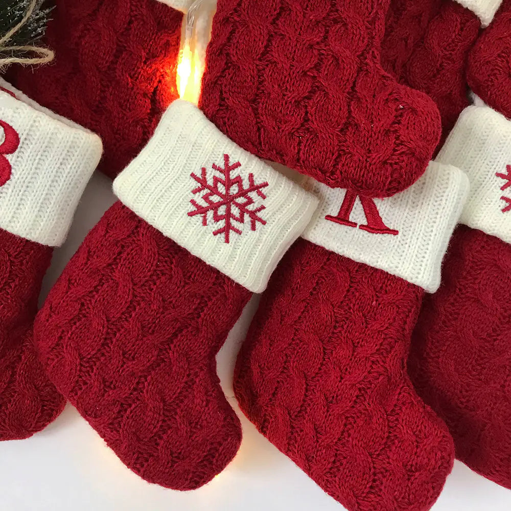 Red knitted stockings with white cuffs featuring snowflake and star designs, hanging together.