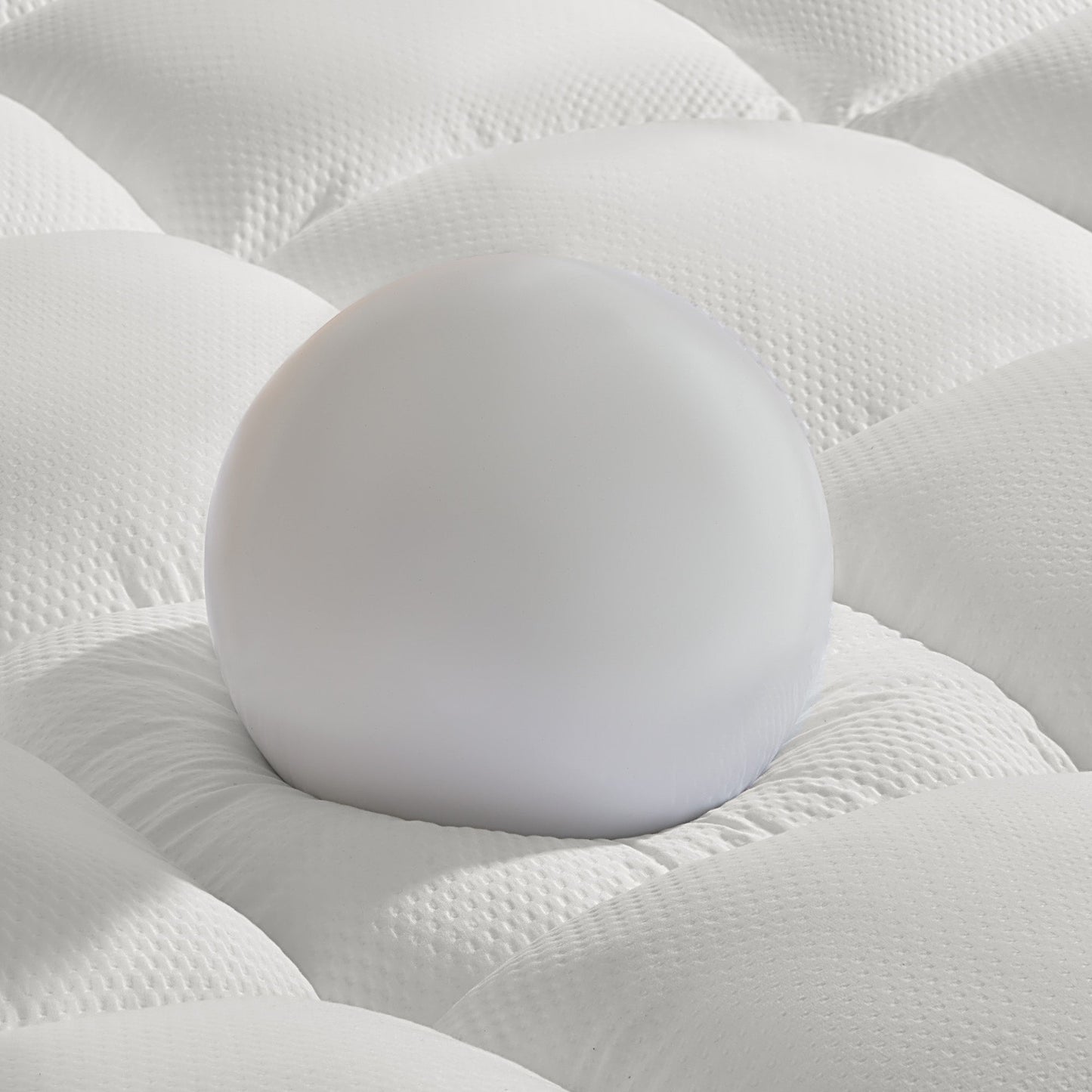 Close-up of a white mattress with a ball in the center