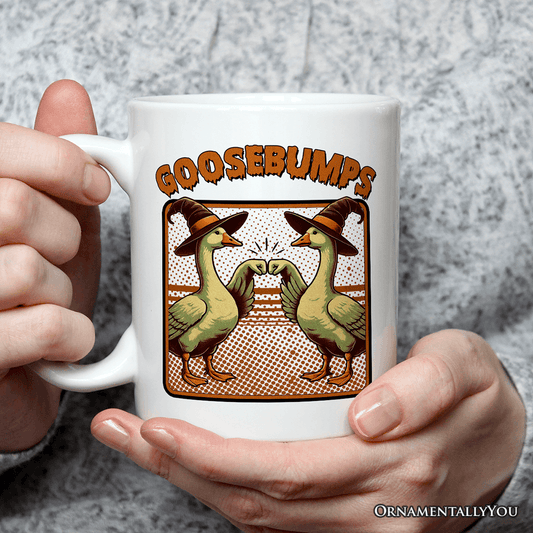 White mug with 'GOOSEBUMPS' design featuring ducks wearing hats, held by a person.