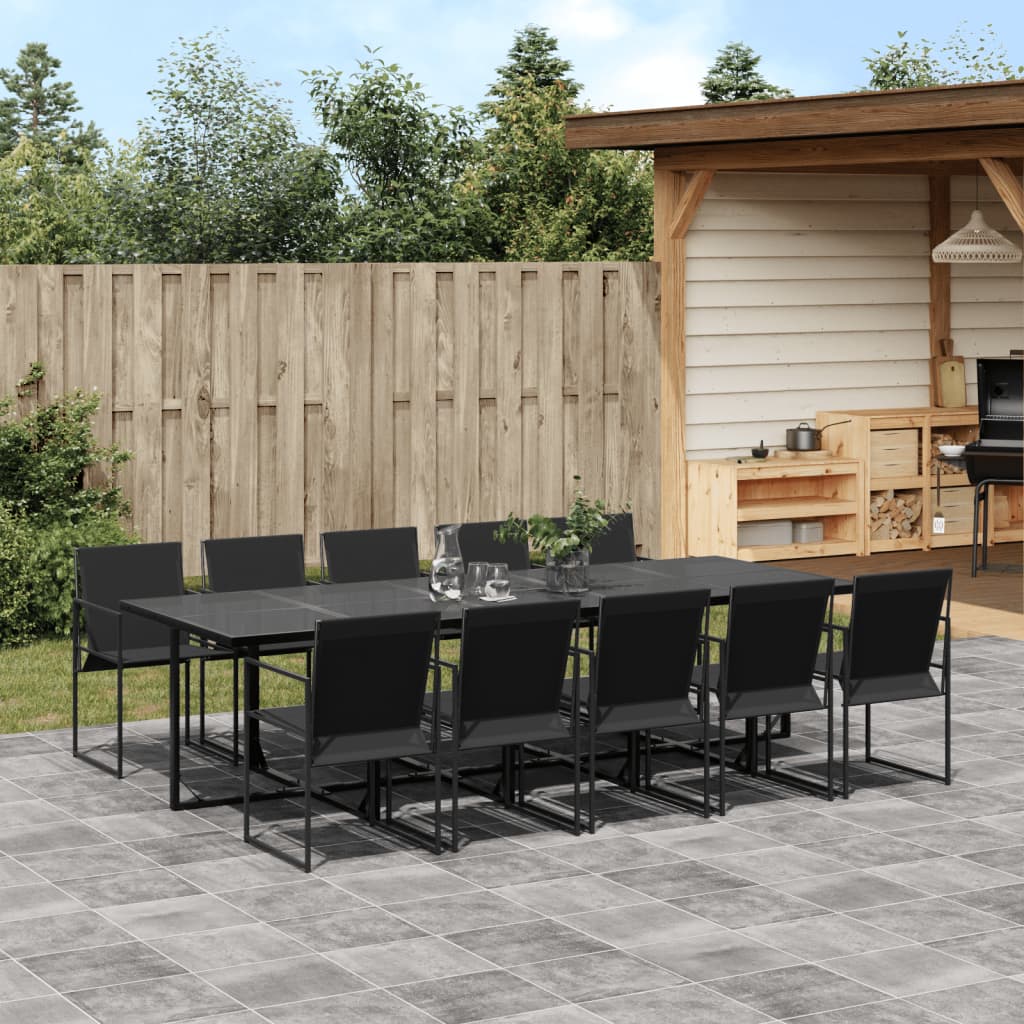 Outdoor patio set with black table and chairs on a patio area with a wooden fence and trees in the background.