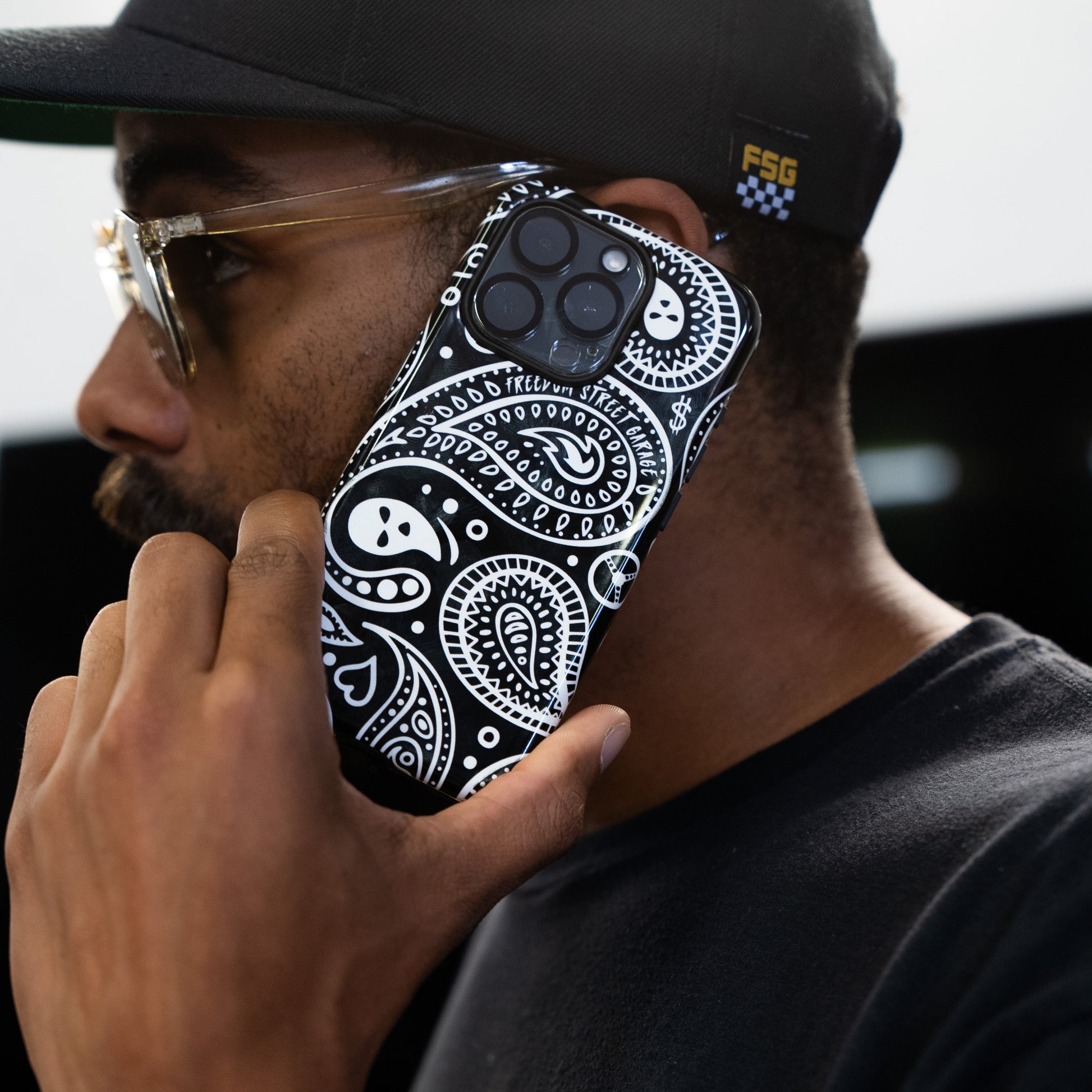 Person holding a phone with a black and white patterned case