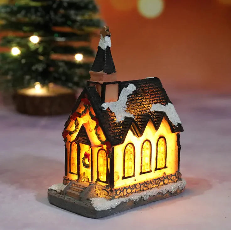 Decorative lit church model with a Christmas tree in the background