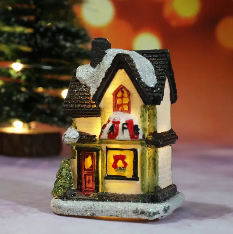 Decorative miniature house with glowing interior lights on a blurred Christmas tree background.
