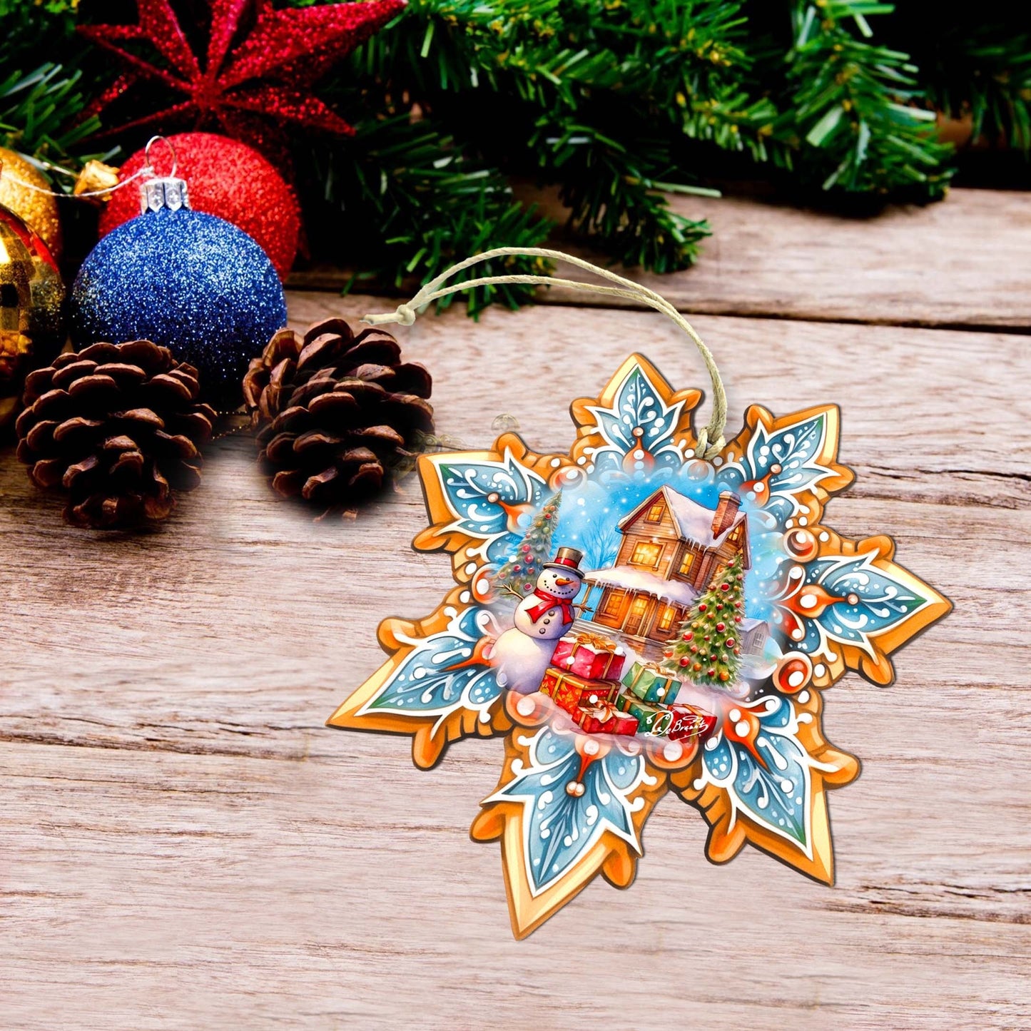 Decorative Christmas ornament with a snowy village scene on a wooden surface with pine cones and ornaments.