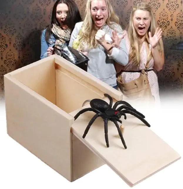 Wooden box with a spider toy, causing surprise among three people.