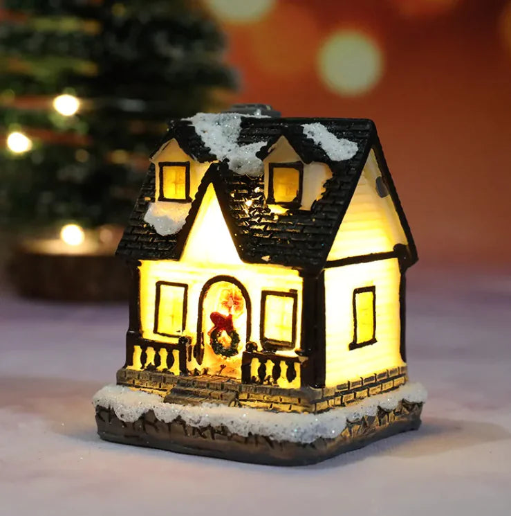 Decorative Christmas house light with a snowy roof and glowing interior, set against a blurred festive background.