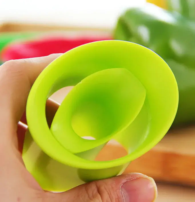 Green silicone lid held by a hand with vegetables in the background