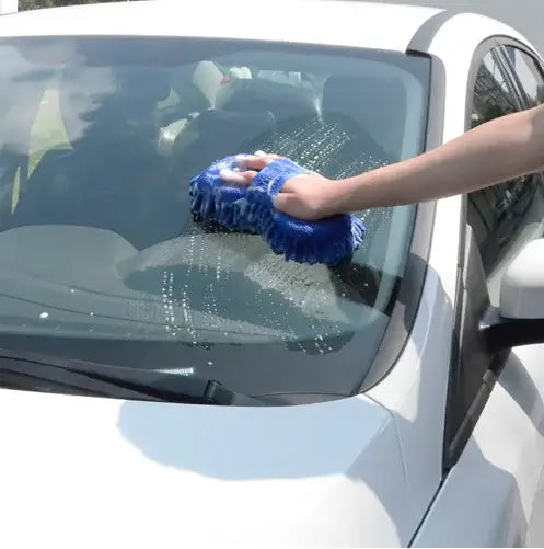 Person cleaning a car window with a blue microfiber cloth